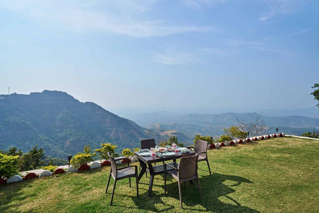 Lawn dining table at the cliff edge overlooking the Sahyadri hills and valleys